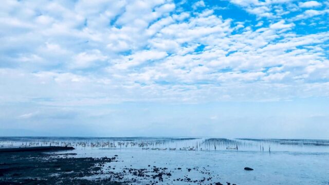 広がる海と空、水平線上に並ぶ漁の支柱