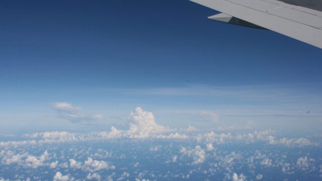 飛行機の窓から見た広がる雲海と青空。自由な旅を象徴する機上の風景。