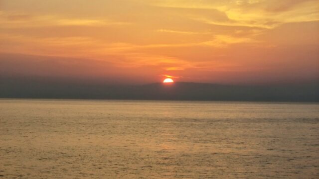 夕日の海に沈む太陽と穏やかな水平線──自由で構造的な収入設計を象徴する風景